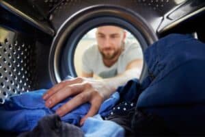 Man doing laundry-10 Hacks To Save Money On Your AC Bill-Allgeier Air-Louisville KY-600x400jpg
