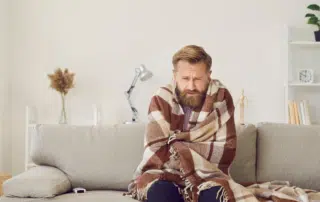 Guy in blanket on couch-5 Reasons Your Furnace May Be Overheating-Allgeier Air-Louisville KY-1100x495jpg