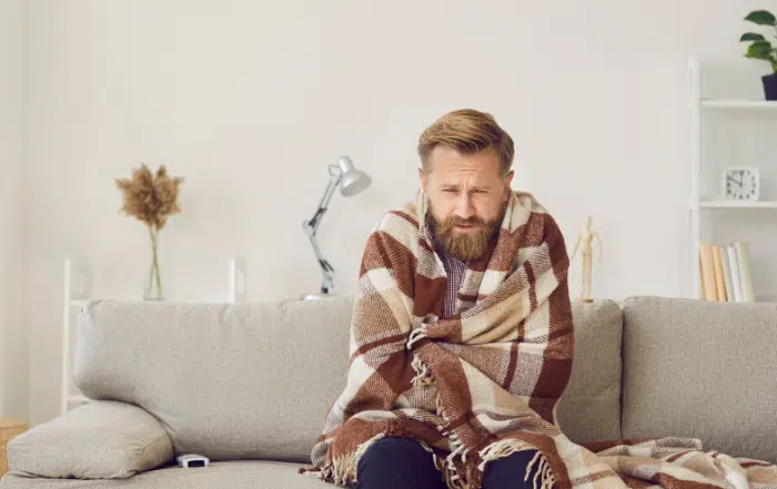 Guy in blanket on couch-5 Reasons Your Furnace May Be Overheating-Allgeier Air-Louisville KY-1100x495jpg